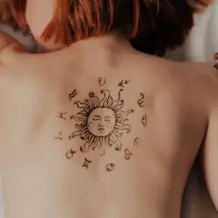 Tatuaż słońca z symbolami zodiaku na plecach. Może to symbolizować ascendent w Koziorożcu, wskazując na determinację i ambicję.