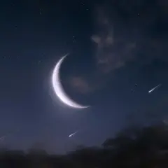 Nocne niebo z jasnym, sierpowatym księżycem w Bliznietach i spadającymi gwiazdami.