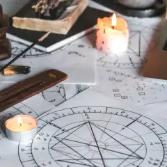 Na stole leżą wykresy astrologiczne, świece, kadzidełko i laptop. Czas na obliczanie ascendentu.