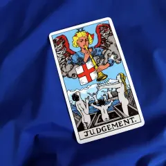 Karta Sąd Ostateczny z talii tarot. Anioł gra na trąbie, budząc ludzi z grobów.