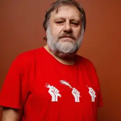 Mężczyzna z siwą brodą w czerwonej koszulce z symbolem trzech pięści trzymających narzędzia. Numerologiczna 33 mężczyzna, filozof.