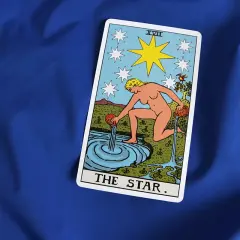 Karta Gwiazda Tarot symbolizuje nadzieję i spokój w uczuciach. Kobieta wylewa wodę, odnawiając życie.