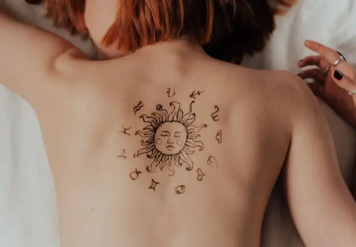 Tatuaż słońca z symbolami zodiaku na plecach. Może to symbolizować ascendent w Koziorożcu, wskazując na determinację i ambicję.
