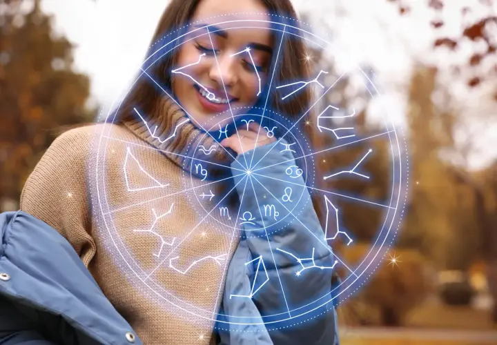 Uśmiechnięta kobieta w swetrze i kurtce, otoczona przez koło zodiaku. Numerologia 11 i 11.