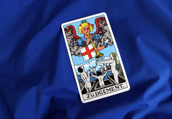 Karta Sąd Ostateczny z talii tarot. Anioł gra na trąbie, budząc ludzi z grobów.