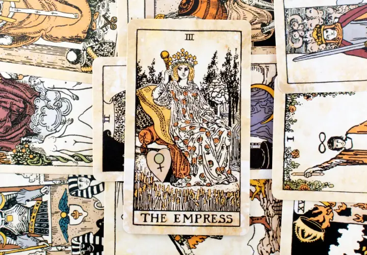 Karta cesarzowa tarot, przedstawiająca kobietę w koronie, siedzącą na tronie, otoczona symbolami płodności i natury.