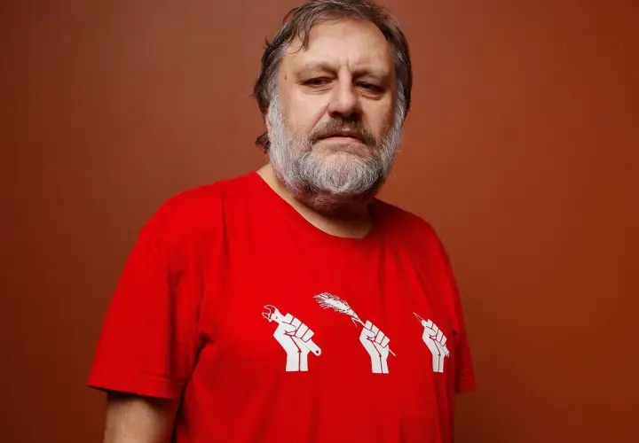 Mężczyzna z siwą brodą w czerwonej koszulce z symbolem trzech pięści trzymających narzędzia. Numerologiczna 33 mężczyzna, filozof.