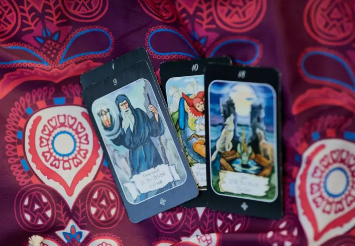 Karty tarota: IX Pustelnik, X Koło Fortuny, XVIII Księżyc. Tajemnicze obrazy na fioletowym tle, które pomogą zrozumieć, tarot co to.
