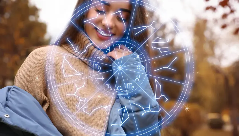 Uśmiechnięta kobieta w swetrze i kurtce, otoczona przez koło zodiaku. Numerologia 11 i 11.