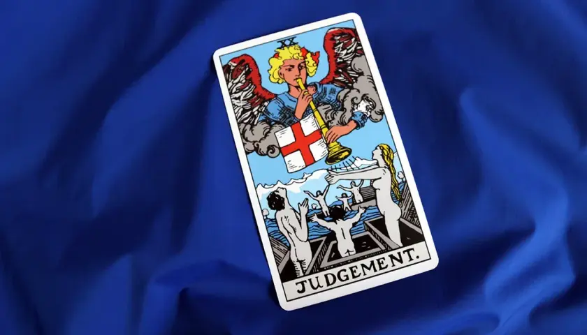 Karta Sąd Ostateczny z talii tarot. Anioł gra na trąbie, budząc ludzi z grobów.