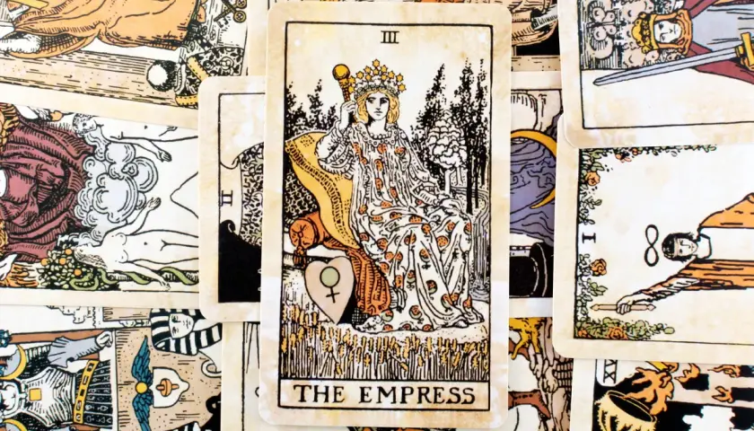 Karta cesarzowa tarot, przedstawiająca kobietę w koronie, siedzącą na tronie, otoczona symbolami płodności i natury.