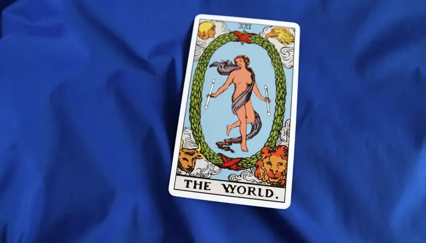 Karta **the world tarot** przedstawia nagą postać w tańcu, otoczoną wieńcem i symbolami czterech ewangelistów.