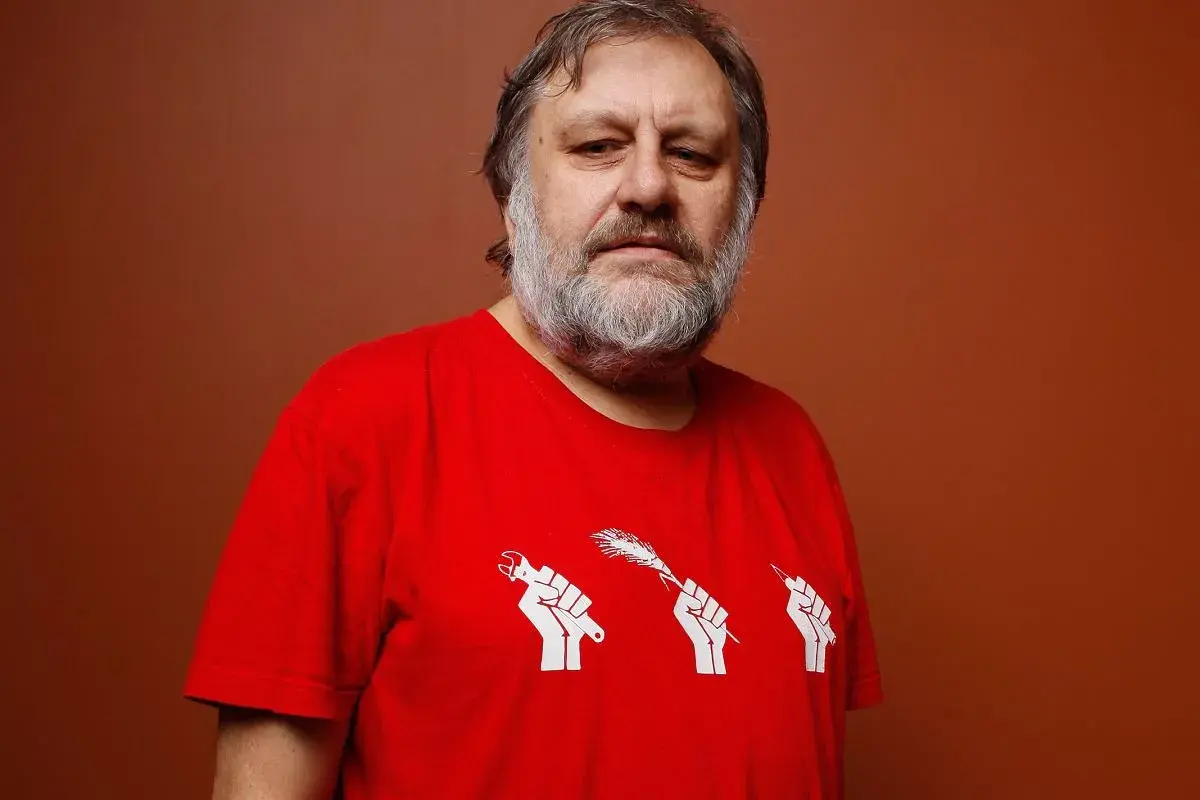 Mężczyzna z siwą brodą w czerwonej koszulce z symbolem trzech pięści trzymających narzędzia. Numerologiczna 33 mężczyzna, filozof.