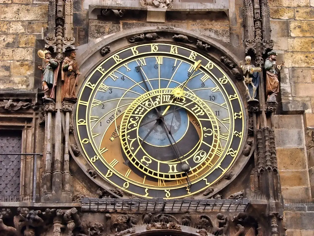 Zegar astronomiczny z figurkami i symbolami. Numerologia 12 widoczna na tarczy.