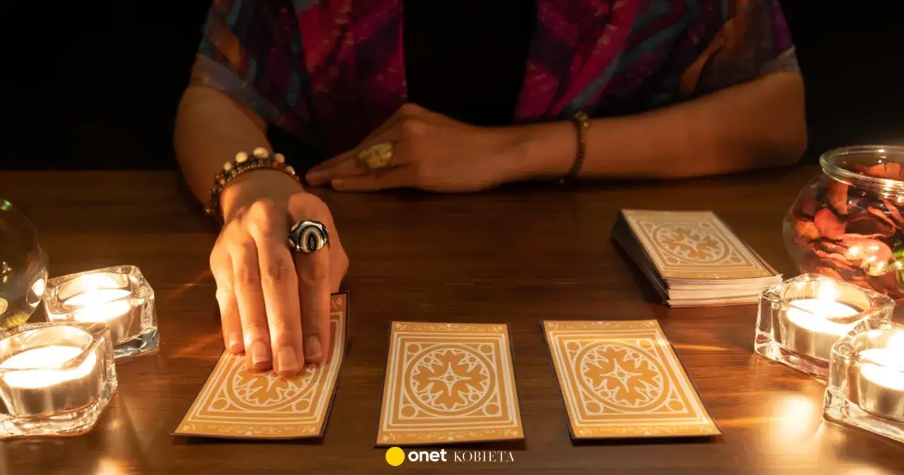 Dłoń z pierścieniem wybiera karty tarot. Czy to będzie