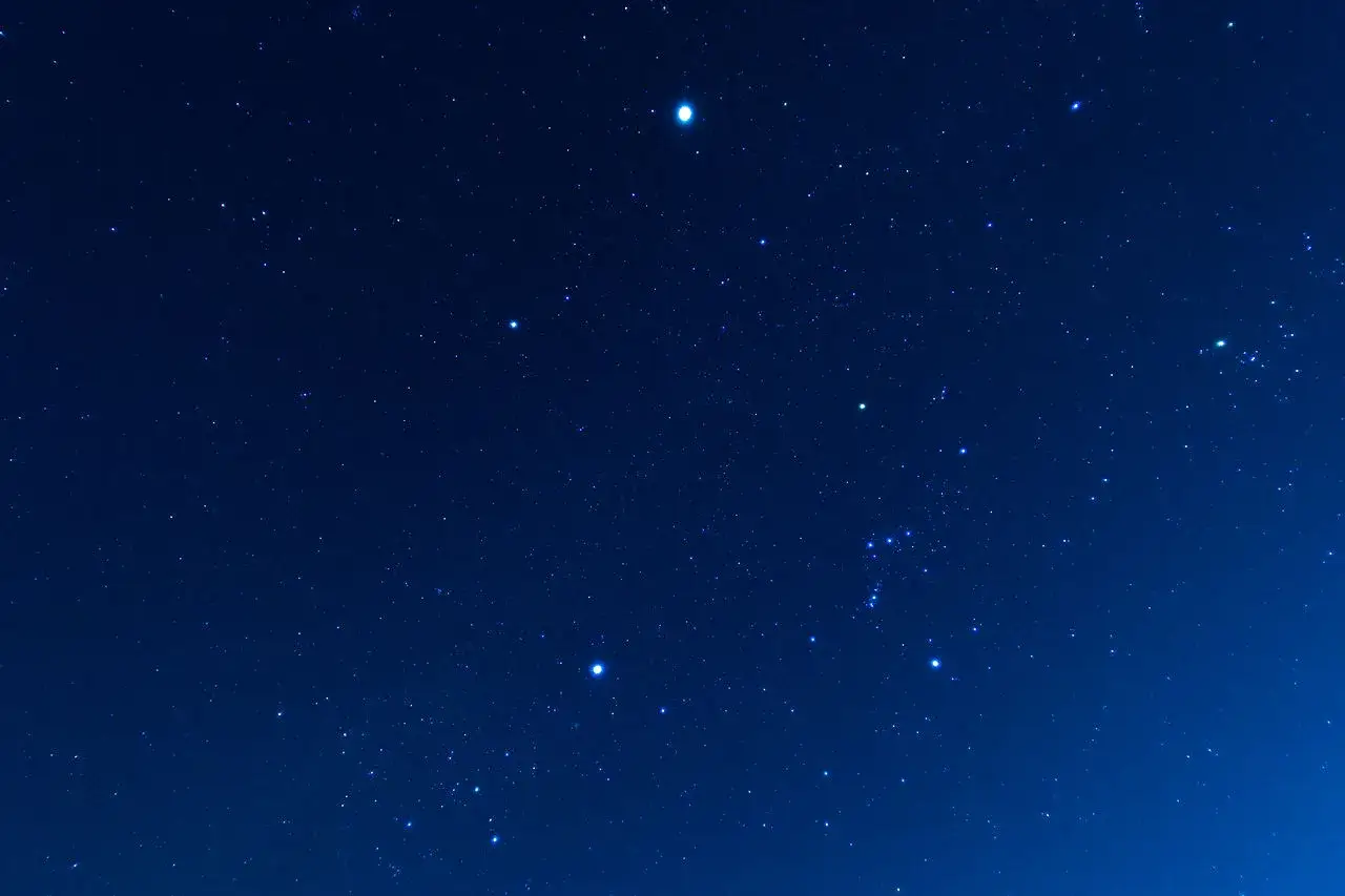 Nocne niebo pełne gwiazd, z widocznym jasnym Syriuszem, najjaśniejszą gwiazdą na nocnym niebie.